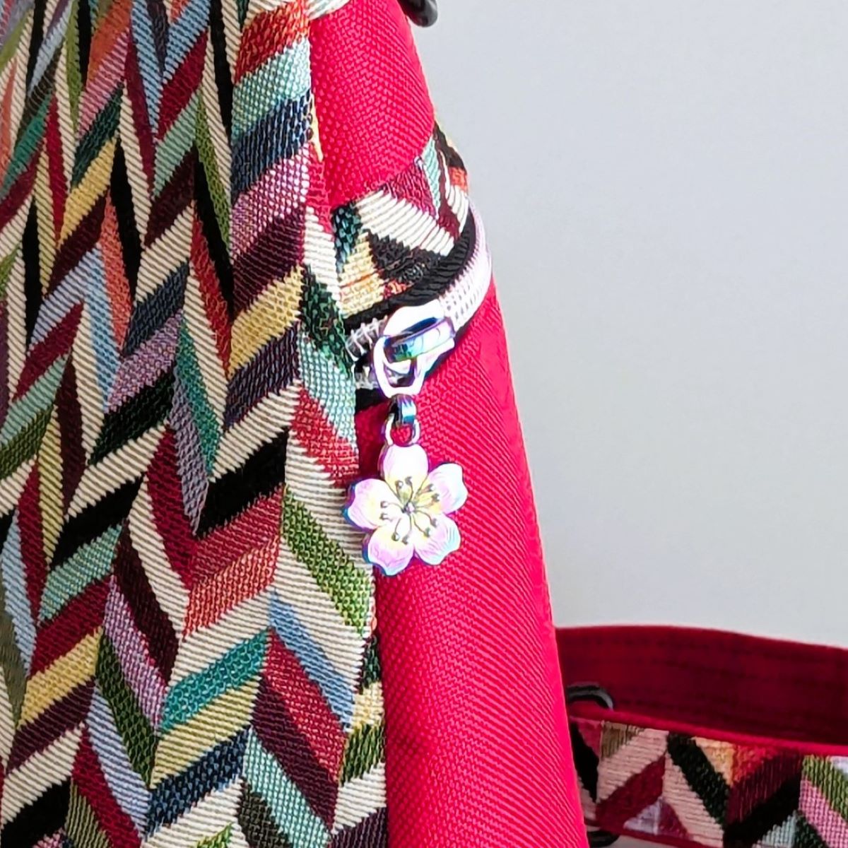 Détail curseur original et breloque fleur sur fermeture éclair de sac rayé multicolore