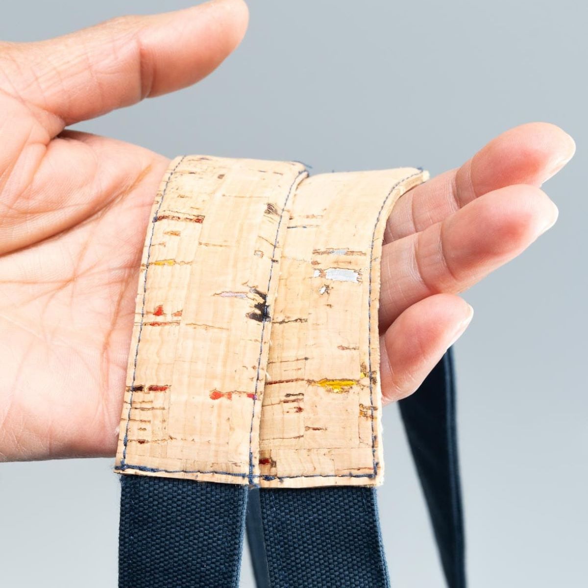 Main montrant des anses de sac bleur renforcées par du liège.