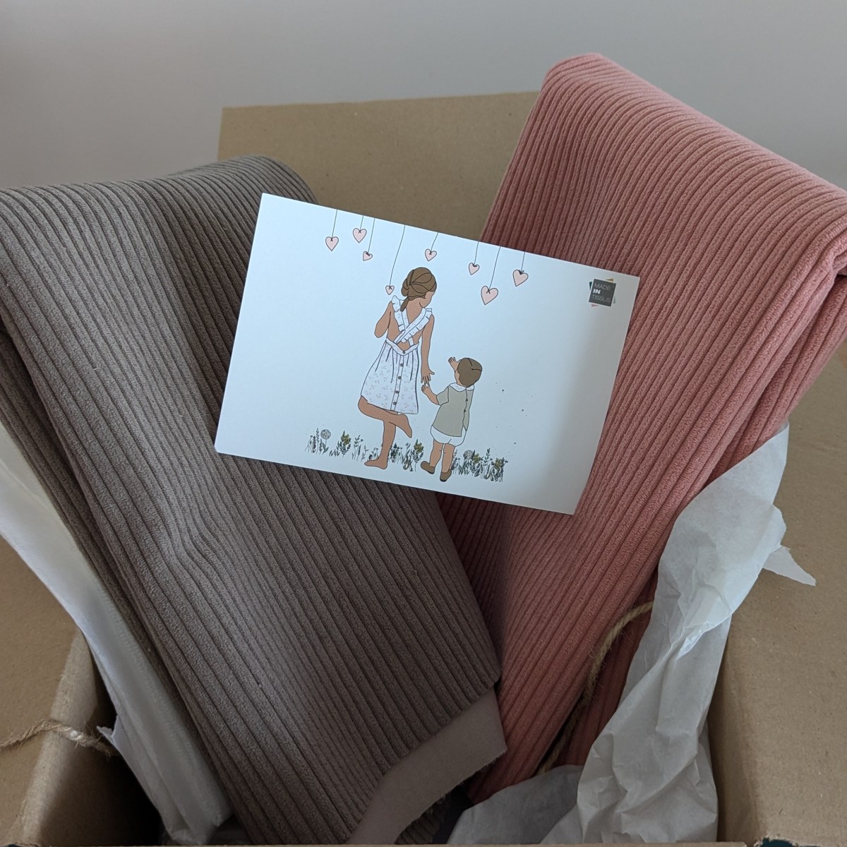 colis carton contenant du tissu velours cotelé rose et taupe