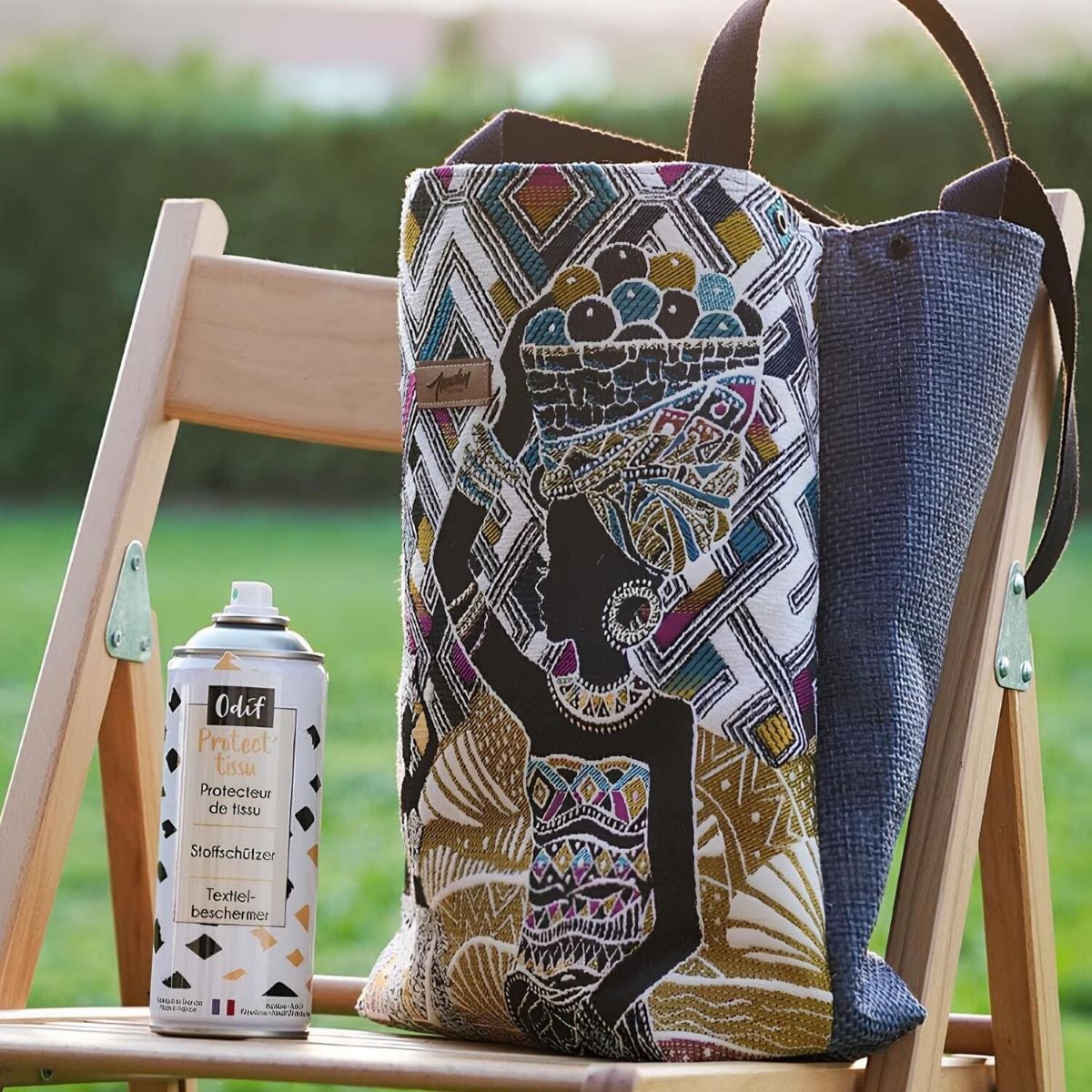 Spray protecteur de tissu posé sur une chaise à coté d'un sac en tissu.