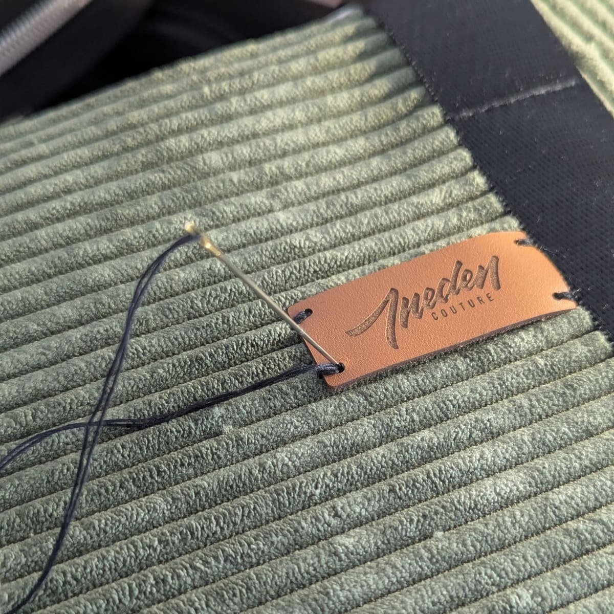 Pose de l'étiquette Ineden Couture en cuir naturel sur sac velours côtelé vert olive - couture main