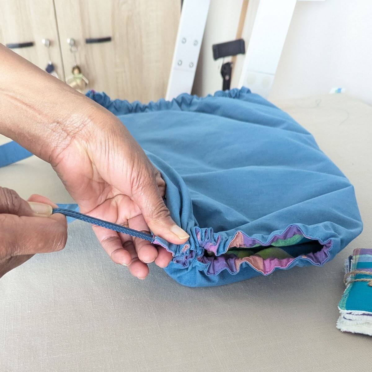 Main resserrant le cordon latéral du tapis de change nomade Ti'Posé pour le transformer en sac