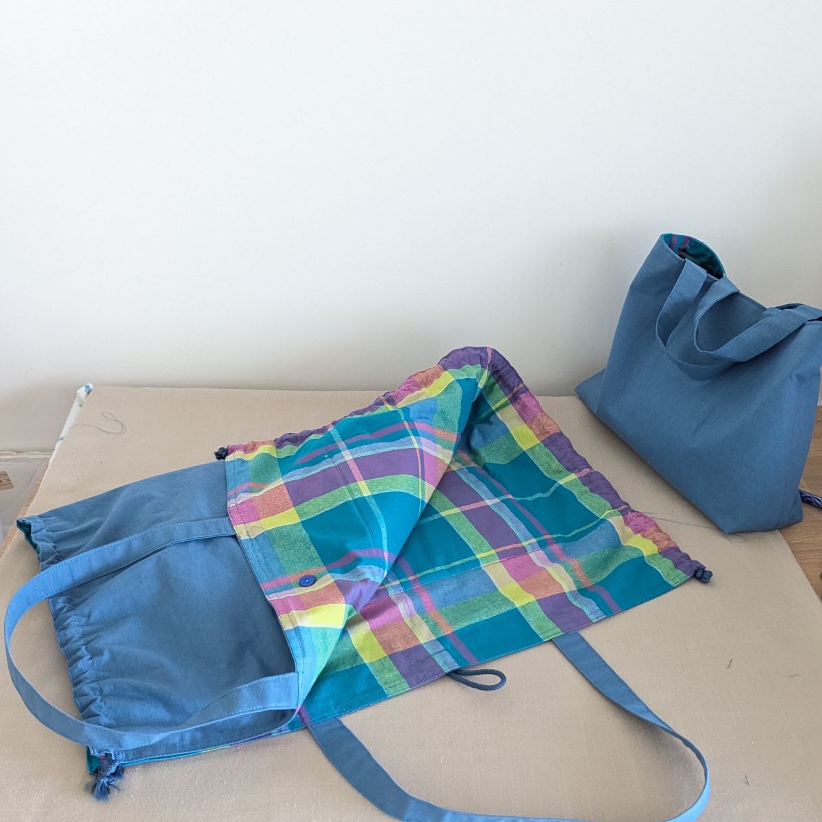 Tapis de change nomade Ti'Posé plié révélant le tissu madras tons bleus